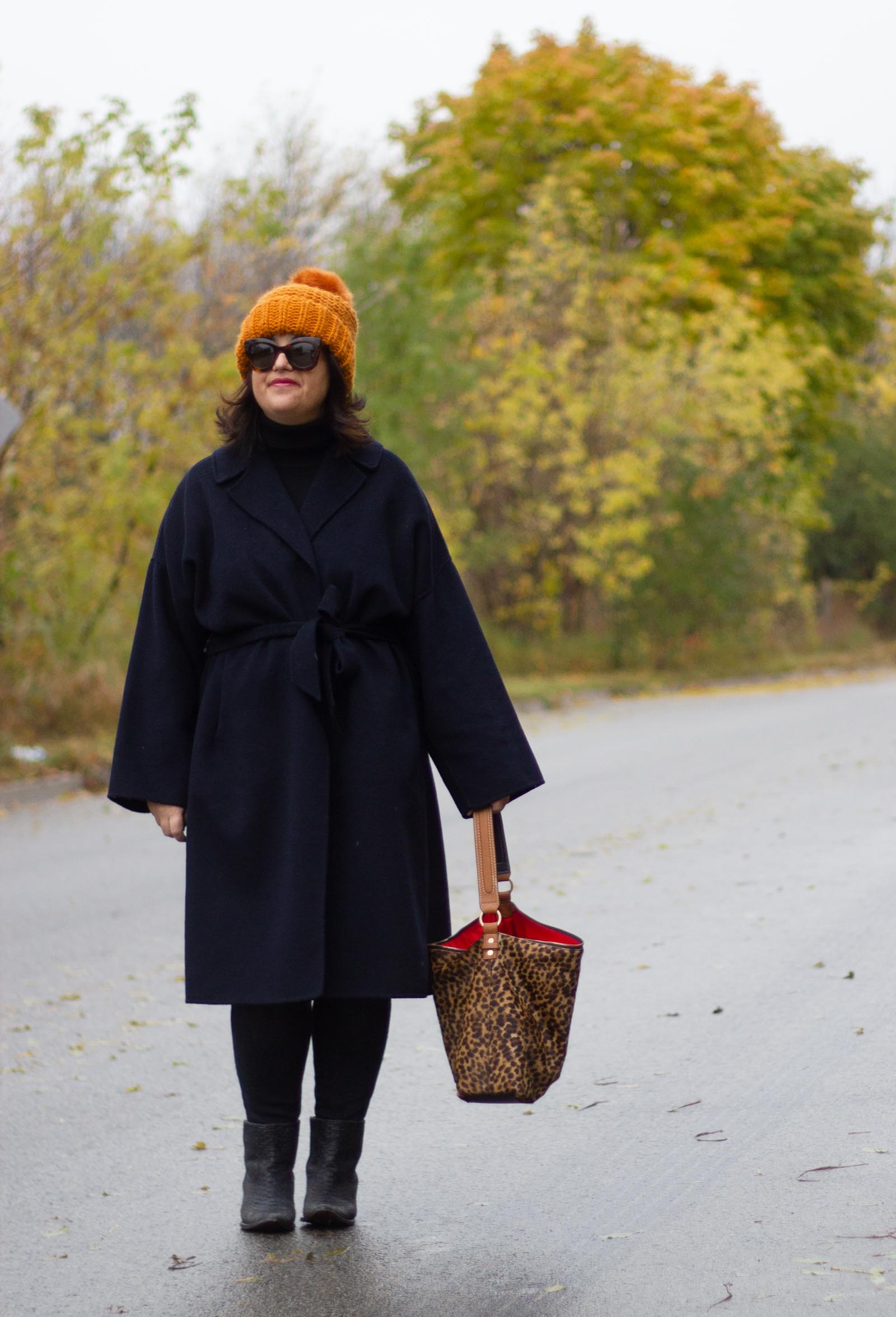 navy wrap coat, black turtleneck, burnt orange hat, leopard bag. 