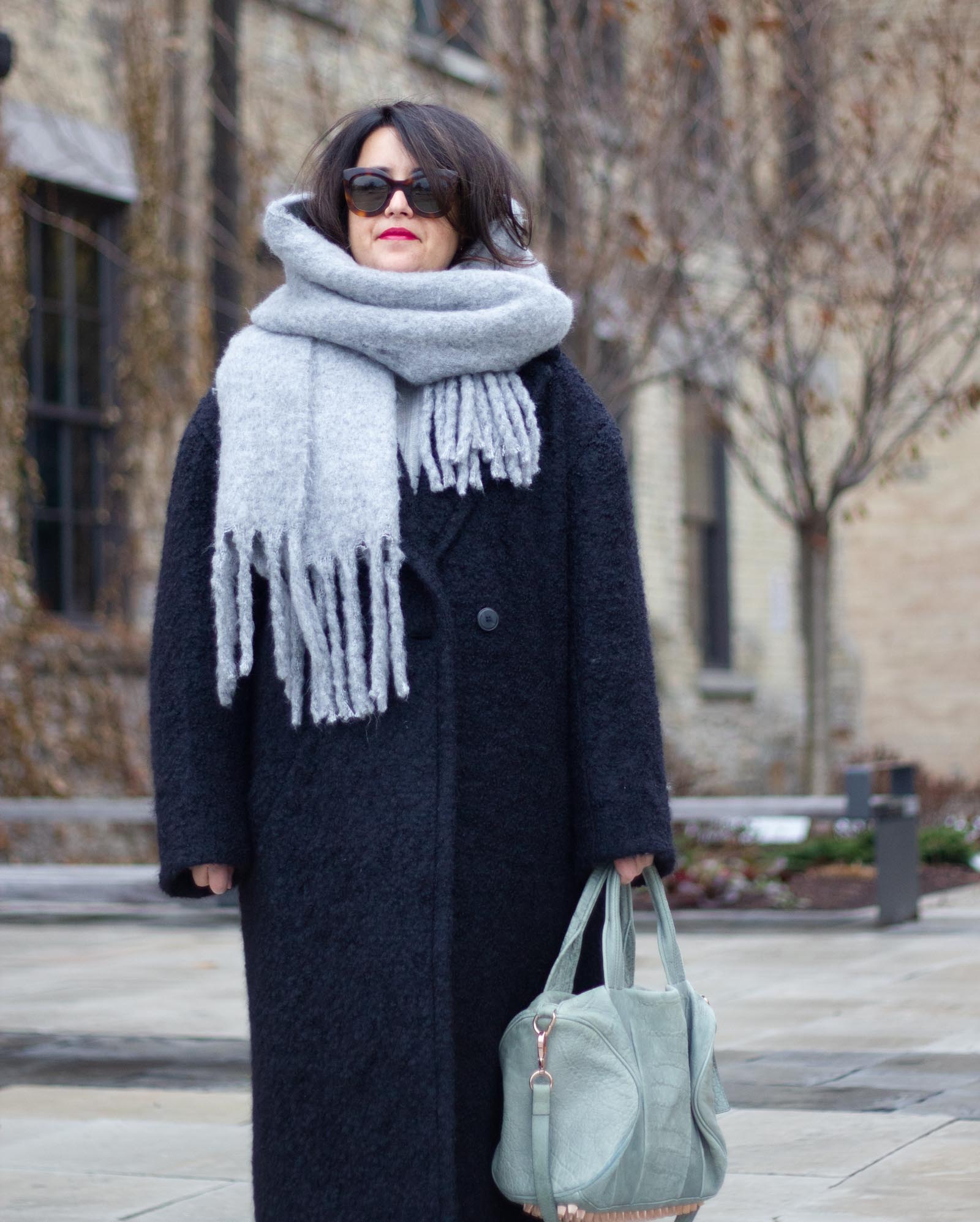 black coat with grey accents, fuzzy grey scarf, rocco bag