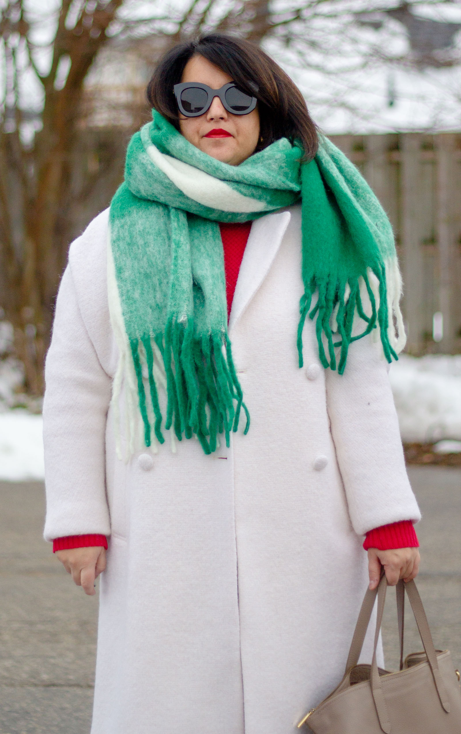 white winter coat with green scarf and red sweater