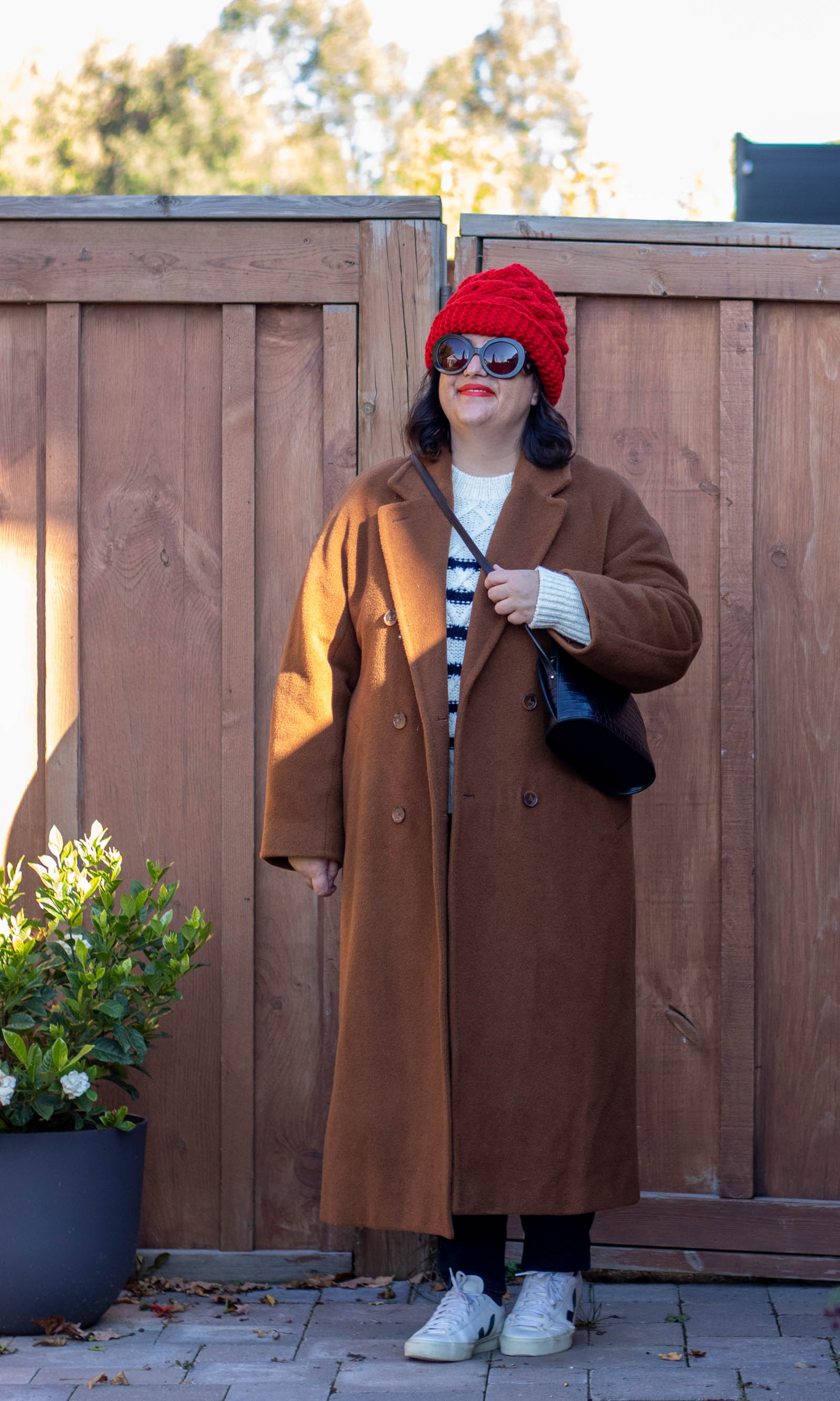 camel coat, stripe sweater, red hat